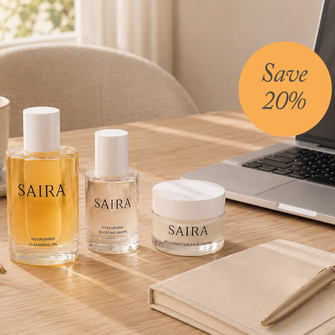 Three Saira skincare products arranged on a wooden desk: a cleansing oil bottle, a hydrating serum bottle, and a moisturizing cream jar. A laptop, notebook, and pen are visible in a bright indoor setting, with an orange circular badge reading 'Save 20%'.