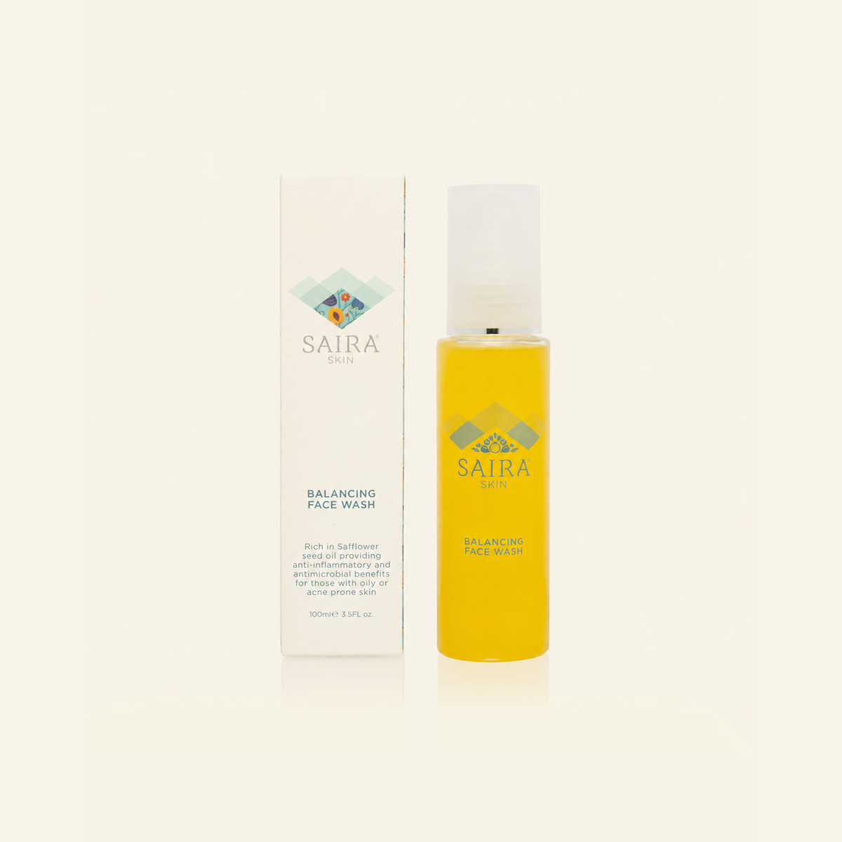 Saira Skin Balancing Face Wash shown in a clear bottle filled with yellow liquid next to its white packaging box, on a light cream background.