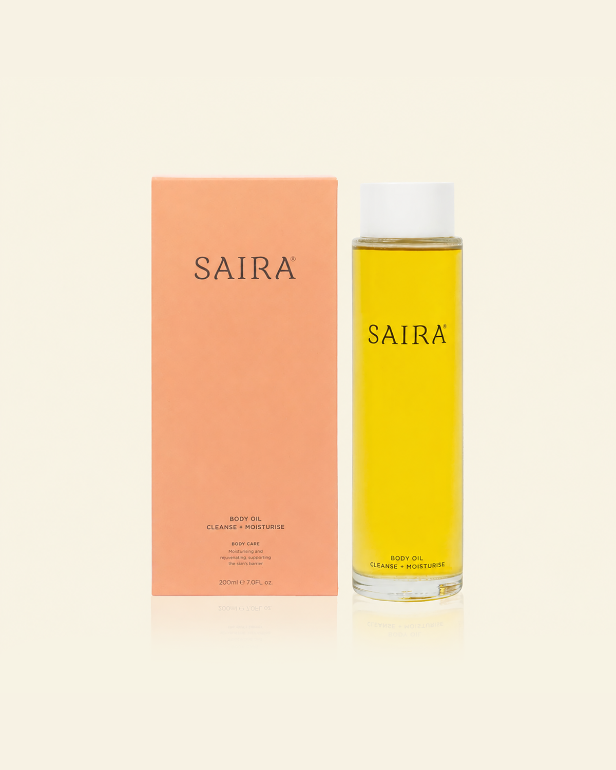 A bottle of Saira body oil next to its peach-colored packaging box, set against a solid cream background.