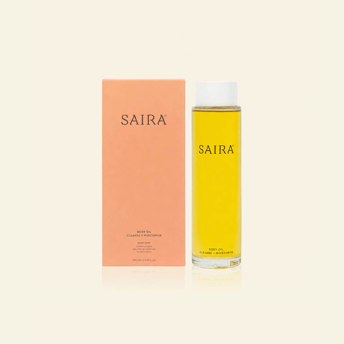 A bottle of Saira body oil next to its peach-colored packaging box, set against a solid cream background.