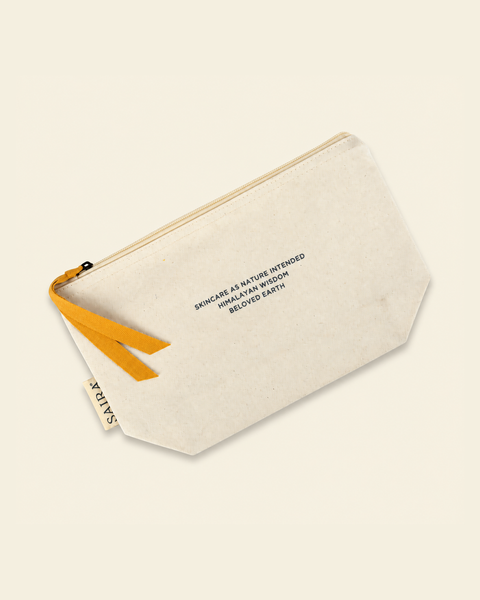 An off-white canvas pouch with a mustard yellow zipper pull and black printed text, shown on a solid cream background.
