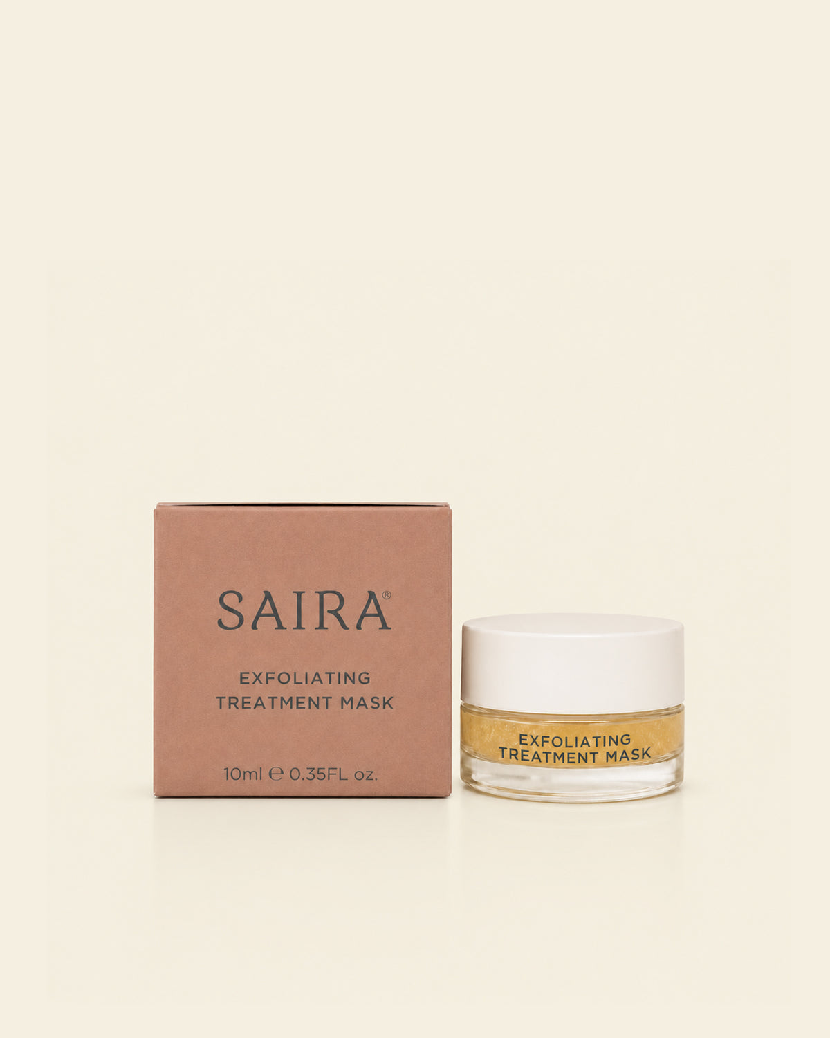 SAIRA Exfoliating Treatment Mask shown with its brown cardboard packaging box and a clear jar containing a golden-yellow mask, set against a solid cream background.