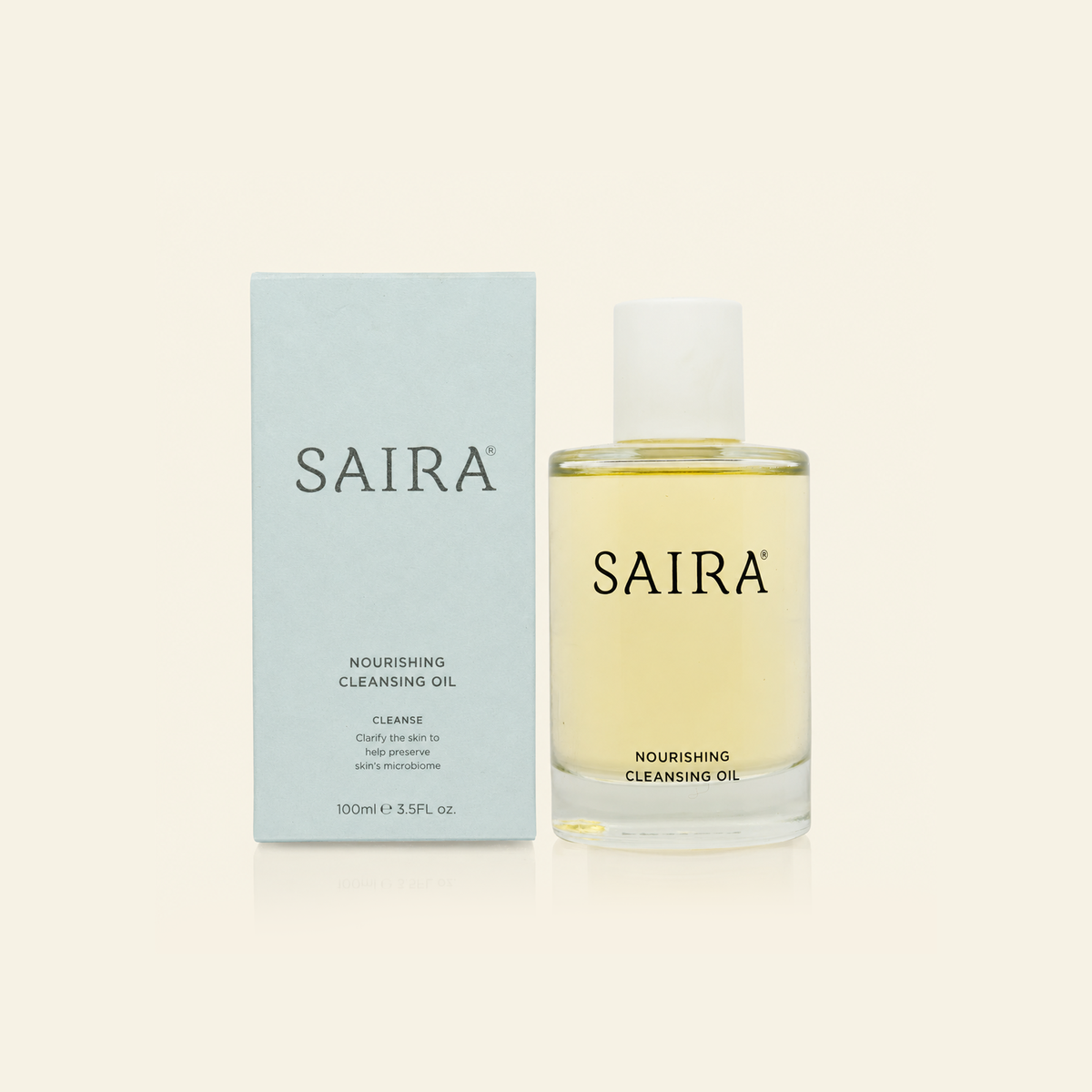 SAIRA Nourishing Cleansing Oil shown in a clear glass bottle next to its light blue packaging box, on a warm off-white background.