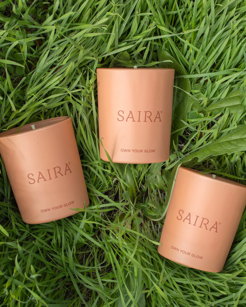 Three terracotta-coloured votive candles nestling in lush green grass