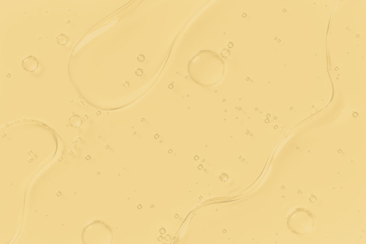 A close-up of a pale yellow translucent liquid with wavy contours and small bubbles, filling the frame.