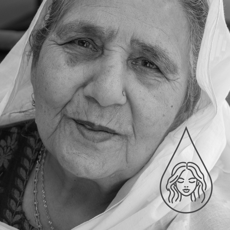Black and white close-up portrait of an elderly woman wearing a white headscarf, with a small teardrop-shaped face illustration overlay near the lower right.